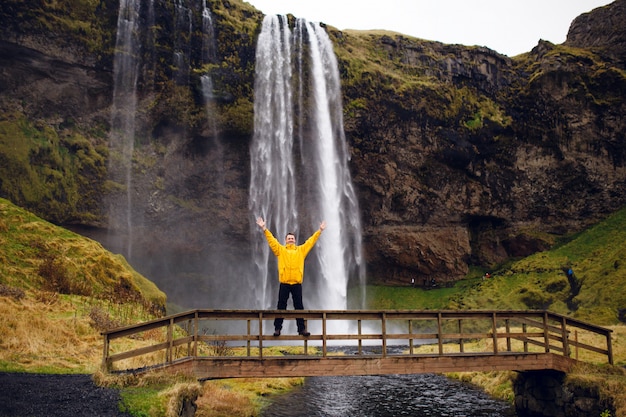 アイスランドの風景の背景にポーズをとって幸せな男