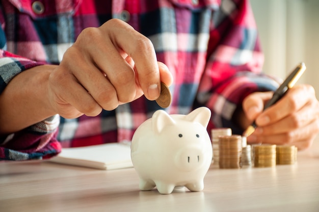 Happy man puts money in a piggy bank