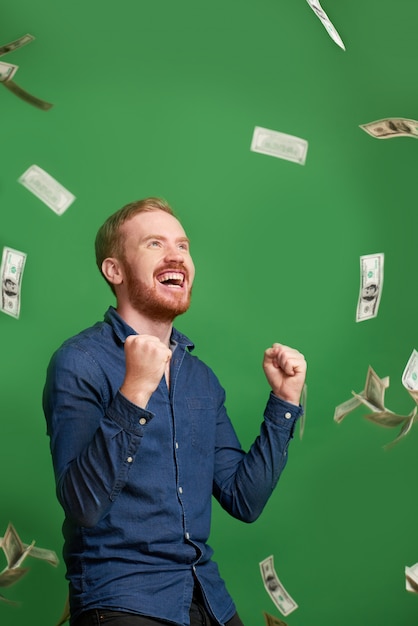 Happy man under rain on money