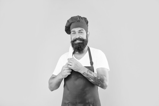 Happy man in red apron and toque holding chefs knife yellow background chef