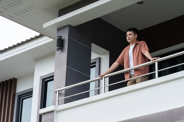 Happy man relaxing and looking from balcony of his home