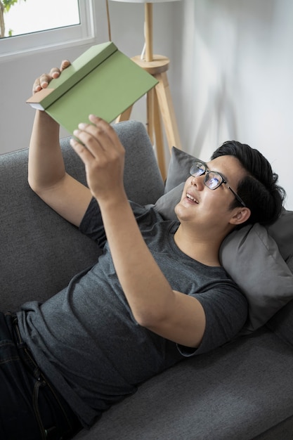 Happy man relaxing on sofa and reading book.