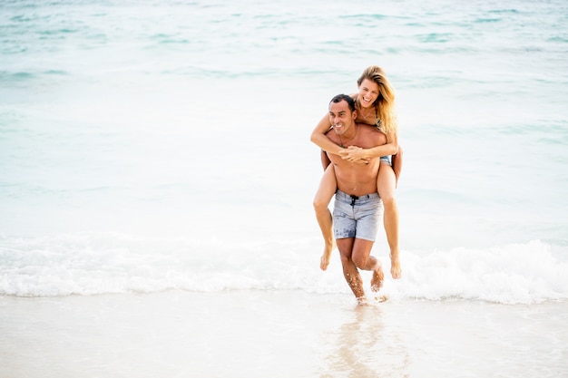 Happy man running carrying girlfriend on shoulder