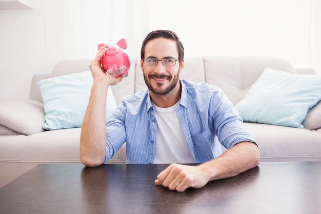 Happy man shaking a pink piggy bank