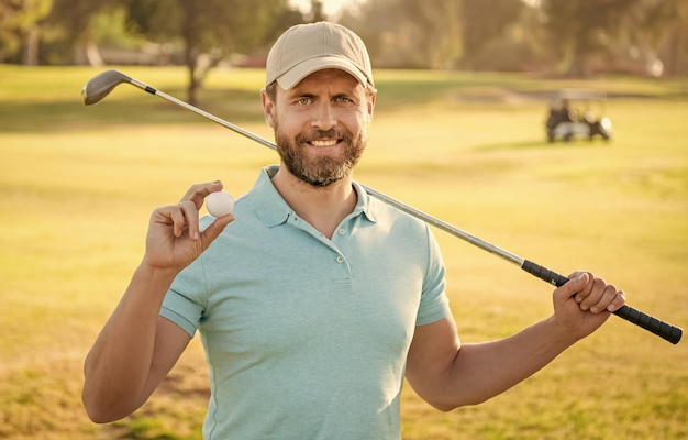 Happy man showing ball of golf game on green grass golf