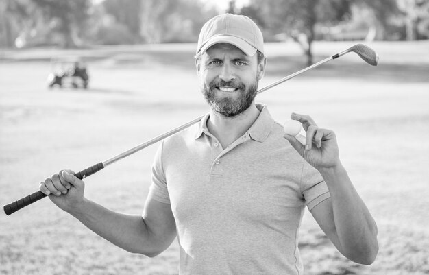 Foto uomo felice che mostra la pallina del gioco di golf sul golf dell'erba verde