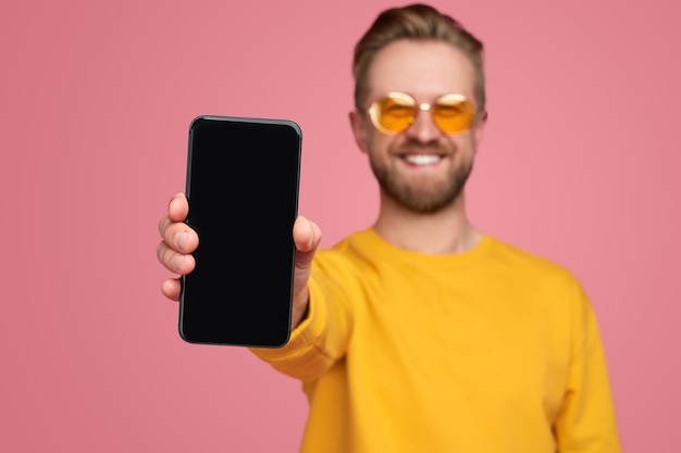 Happy man showing smartphone with black screen at camera