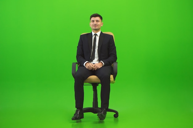 The happy man sit of the chair on the green background