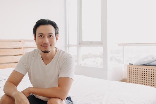 Happy man sit on his bed in his apartment in concept of wellness