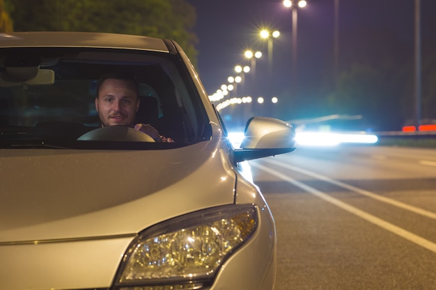 The happy man sit inside the car on the highway. evening night time