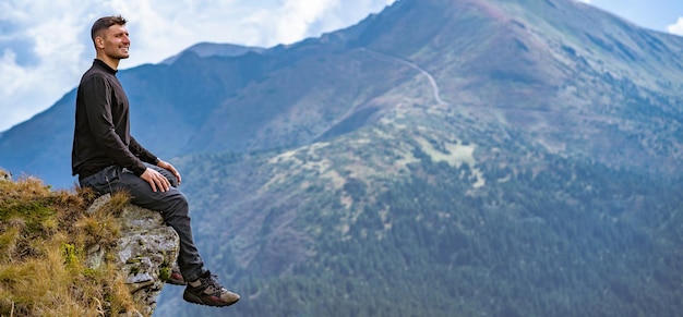 The happy man sitting on the cliff