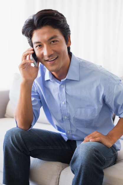 Happy man sitting on couch talking on phone