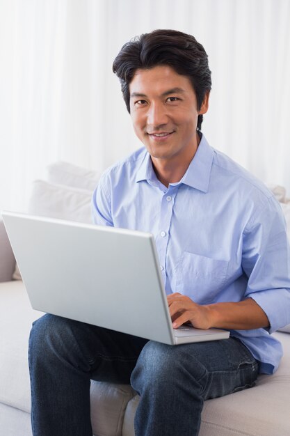 Happy man sitting on couch using laptop 