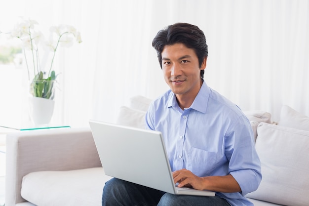 Happy man sitting on couch using laptop 