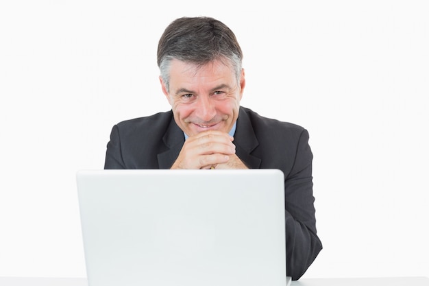 Happy man sitting at his desk with laptop