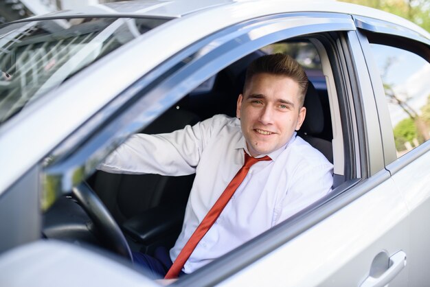 幸せな男は車の中で微笑む。