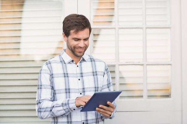 Happy man smiling at camera holding tablet