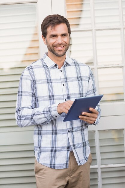 Happy man smiling at camera holding tablet