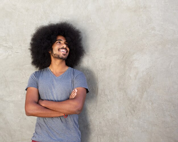 Happy man standing with arms crossed by concrete wall