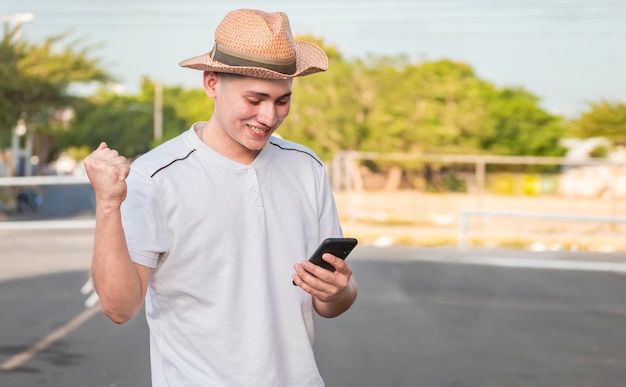 Happy man on the street holding a smartphone and celebrating excited guy looking at his smartphone