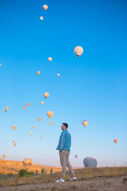 Happy man during sunrise watching hot air balloons in cappadocia turkey