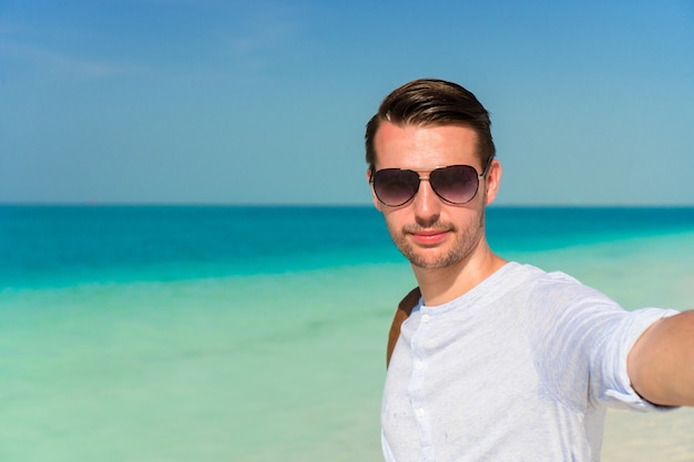 Happy man taking selfie on tropical beach