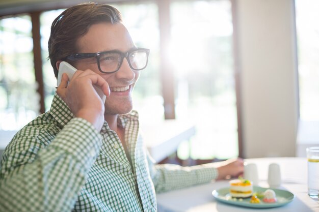 Foto uomo felice che parla sul telefono cellulare mentre pranzando