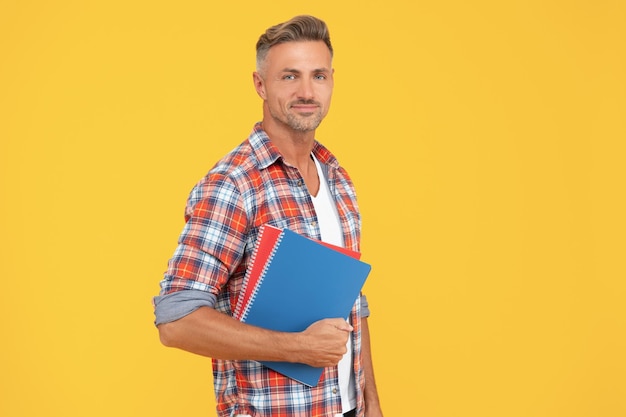 Photo happy man teacher holding school books yellow background education