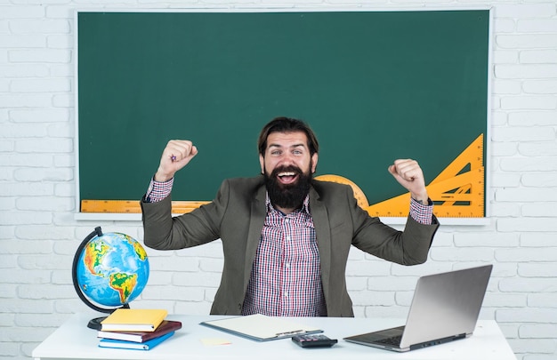 Happy man teacher on laptop screen watching online course modern workplace