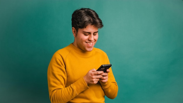 Happy man text messaging via cellphone in studio