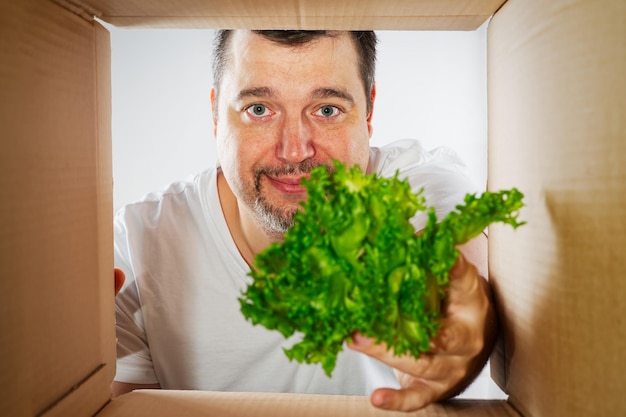 Happy man unpacking opening carton box and looking inside Man smiling unpacking and carton box