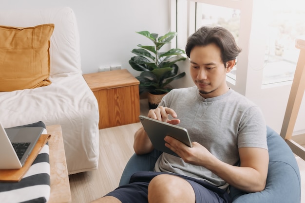 Happy man use tablet for work on bean bag in the living room of the house