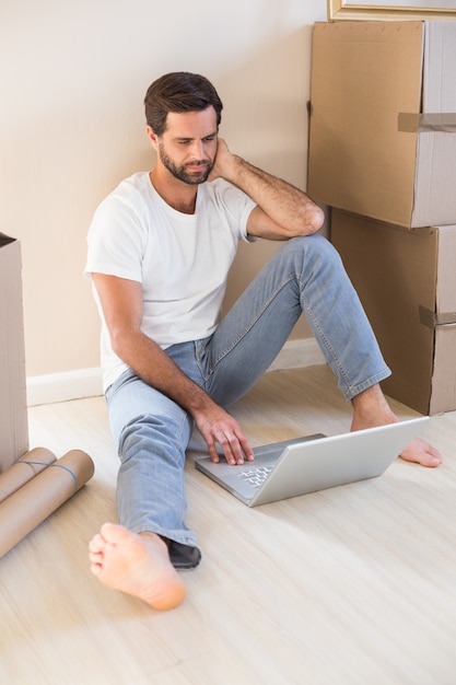 Happy man using laptop surrounded by boxes