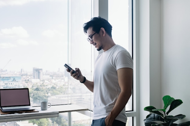 Happy man using smartphone with balcony view