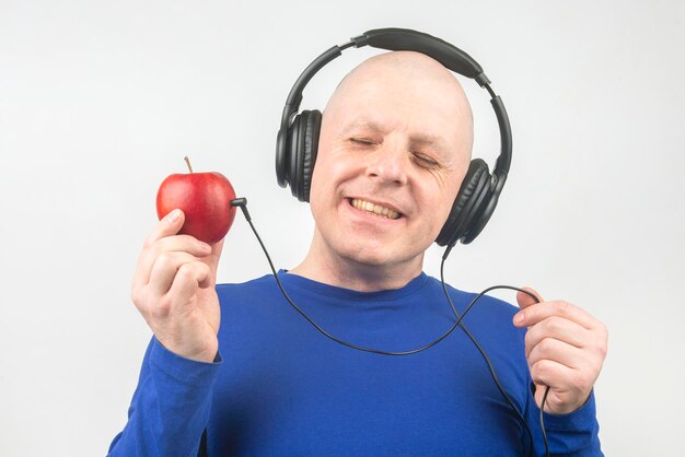 happy man wearing portable full-size headphones listens to music using an apple player.