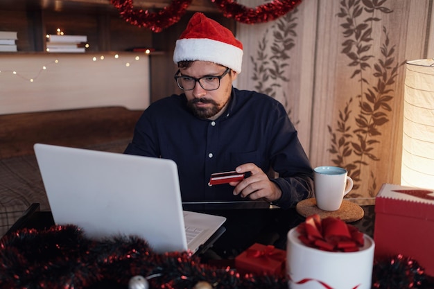 Happy man wearing Santa Claus hat holding gift or credit card