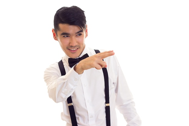 Happy man in white shirt with black bow-tie and black suspenders on white background in studio