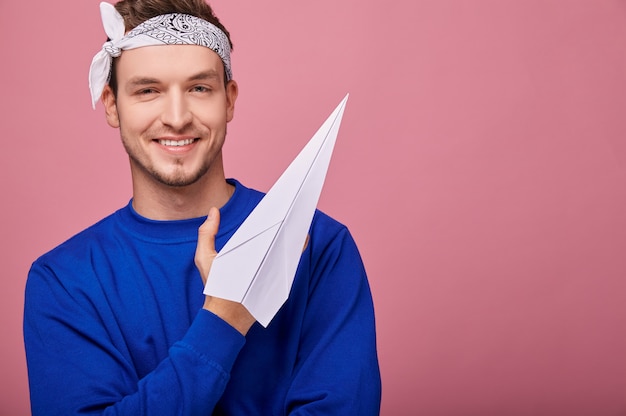 happy man in white with patterns bandanwith white paper airplane