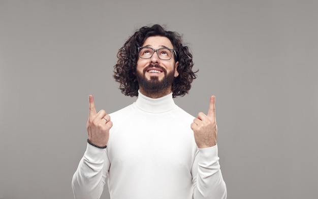 Happy man with beard pointing up in studio