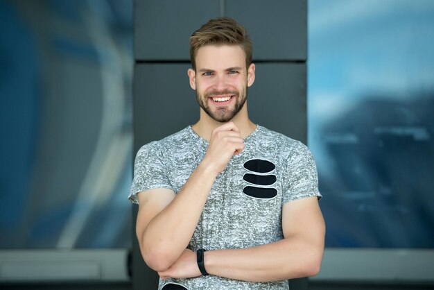 Happy man with beard on smiling face outdoor. Macho smile in grey tshirt. Casual in style. Happy and healthy. Sporty handsome guy. Confidence and charisma.