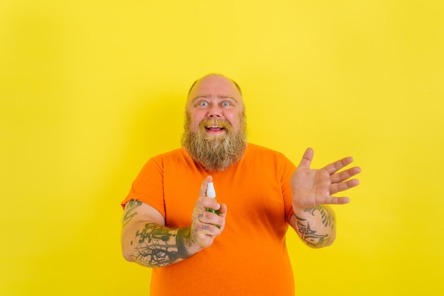 Photo happy man with beard and tattoos holds a hands cleaner against covid