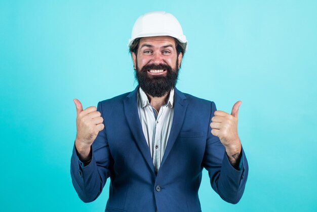 Happy man with beard wear hard hat concept of engineering architecture and building male builder wearing formal suit and helmet for protection working on construction project thumb up examining