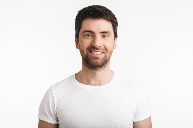 happy man with bristle in casual t-shirt posing on front and smiling isolated over white wall