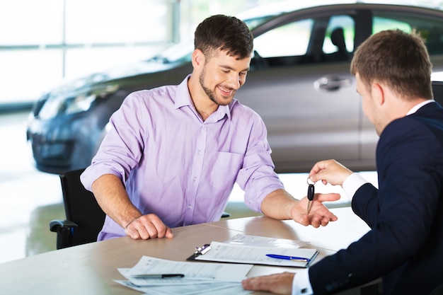 Happy man with car dealer in auto show or salon