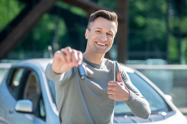 路上の車のキーを持つ幸せな男