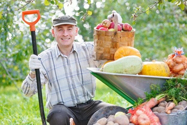 Foto uomo felice con un raccolto in giardino