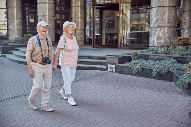 Happy man with a digital camera and a stylish elderly lady walking hand in hand