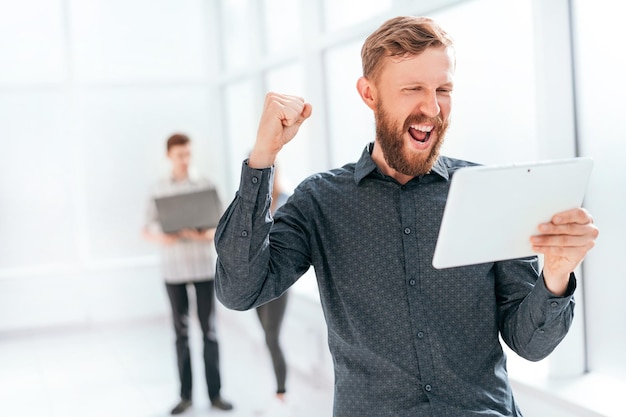 Happy man with digital tablet standing in office lobby