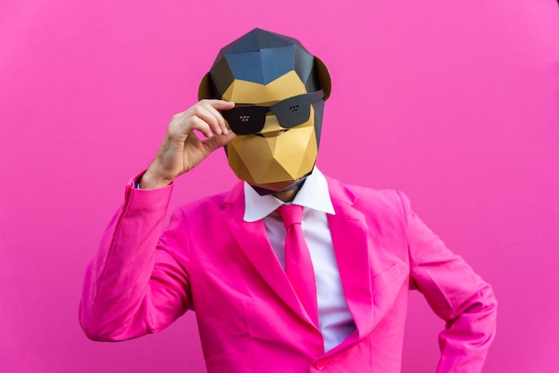 Happy man with funny low poly mask on colored wall  