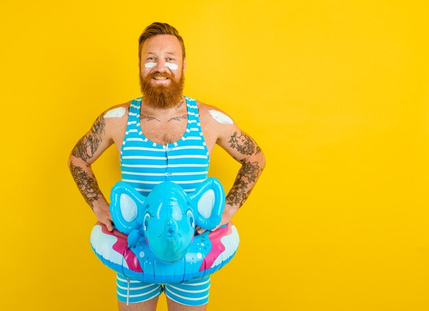 Happy man with inflatable donut with elephant is ready to swim